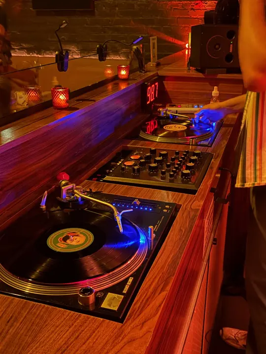 Two turntables and a rotary mixer on a wooden console