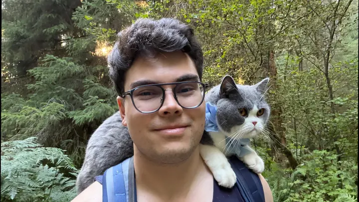 DJ DJ in a forest with Todd, a grey cat, on his shoulder
