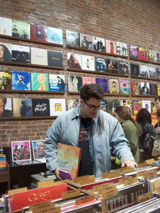 DJ DJ flipping through record bins with an album under his arm